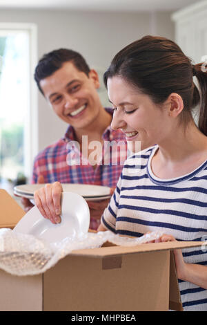 Young Couple Unpacking Boxes In Kitchen On Moving Day Stock Photo