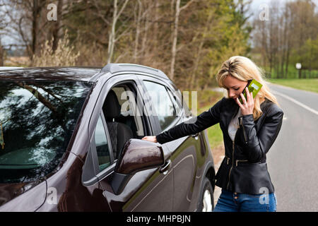 young attractive desperate and confused woman standing next to her car and talking to mobile phone Stock Photo