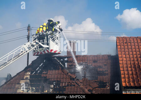 two Fireman with equipment on the Drehleiter ( aerial ladder ) extinguishing fire Stock Photo
