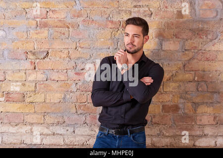 Portrait of a thinking handsome young businessman in a black shirt. Stock Photo