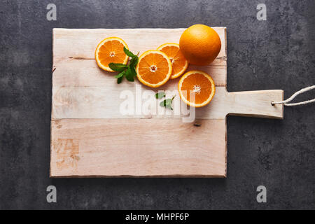 Flat lay of fresh citrus fruits, orange and half cut orange slices on cutting board on black stone background. Horizontal top view with copy space. Stock Photo