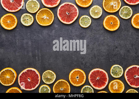 Flat lay of citrus fruits pattern of lemon, orange and grapefruit on black stone background. Copy space in the middle. Top view. Stock Photo