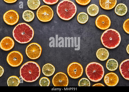 Flat lay of citrus fruits circular pattern of lemon, orange and grapefruit on black stone background. Copy space in the middle. Top view. Stock Photo