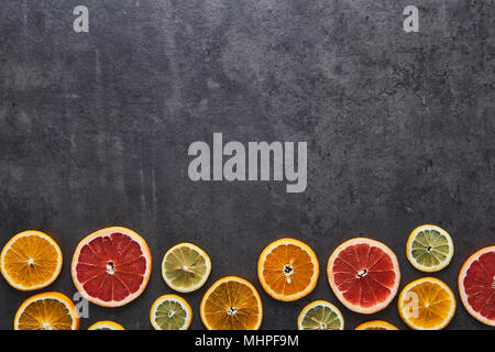 Flat lay of citrus fruits pattern of lemon, orange and grapefruit on black stone background. Copy space above. Top view. Stock Photo