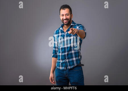 A young black man standing and smiling while pointing in to the camera Stock Photo