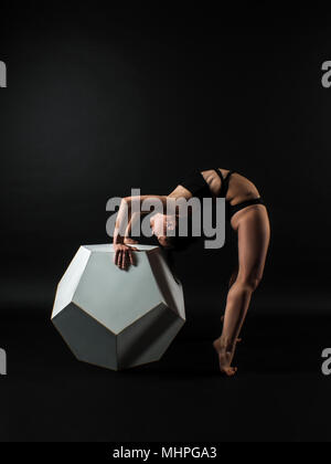 Sporty fit darkhair woman in black sportswear working out in studio with black background. Dancing, streching, Standing pilates, yoga and fitness poses Stock Photo