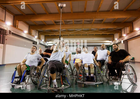 group of smiling disabled basketball players on a wheelchair take a selfie in a basketball court Stock Photo