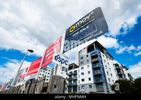 Many sign boards from estate agents for properties for sale and rent outside large modern apartment blocks at western Harbour in Leith, Edinburgh, Sco Stock Photo