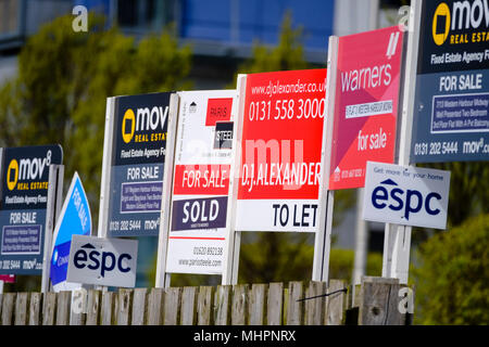 Many sign boards from estate agents for properties for sale and rent outside large modern apartment blocks at western Harbour in Leith, Edinburgh, Sco Stock Photo