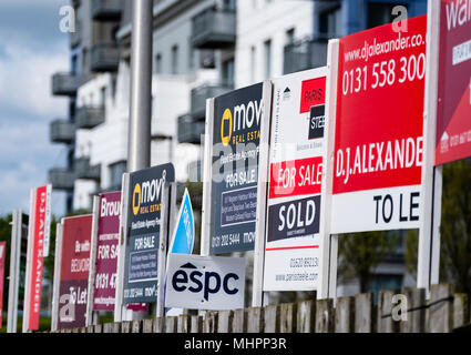 Many sign boards from estate agents for properties for sale and rent outside large modern apartment blocks at western Harbour in Leith, Edinburgh, Sco Stock Photo