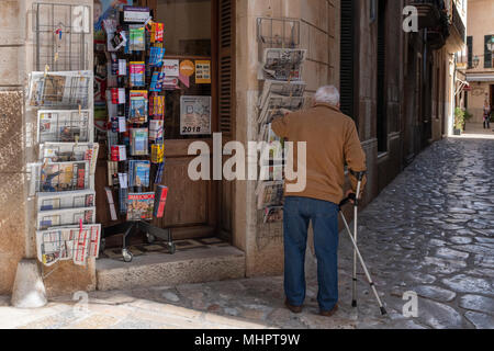 An elderly man outside a newspaper shop in Pollensa town, Mallorca, Spain. Stock Photo