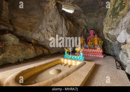 Buddha's footprint and several Buddha statues on altar inside the Tham Sang (or Xang) Cave, also known as the Elephant Cave, near Vang Vieng in Laos. Stock Photo