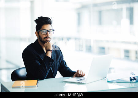 Thoughtful young international male students making concept planning for coursework preparing to making report on lesson while sitting at desk with no Stock Photo