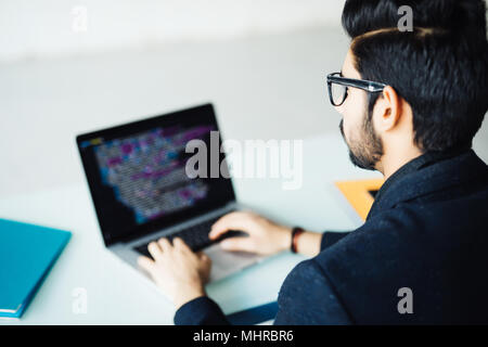 Indian software developer working on computer at his office table Stock Photo