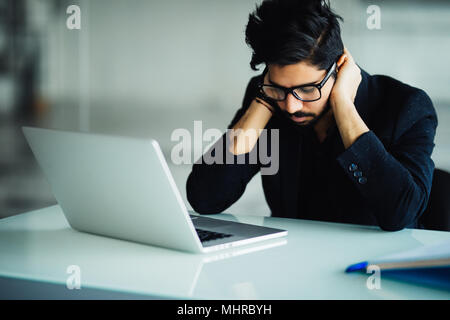 Tired and worried indian business man at workplace in office Stock Photo