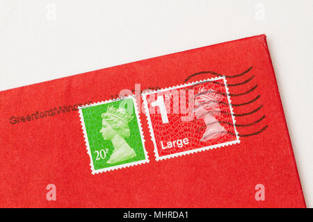 Envelope corner with 2 stamps, ones red, one green, of Queen Elisabeth II. UK postage stamp on red paper. Stock Photo