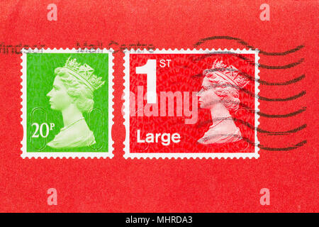 Close up of an envelope with 2 stamps, ones red, one green, of Queen Elisabeth II. UK postage stamp on red paper. Stock Photo