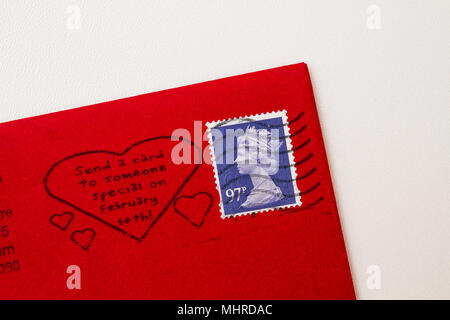 Red envelope corner with a blue stamp of Queen Elisabeth II. UK postage  with Valentine's Day dedication isolated on white background. Stock Photo