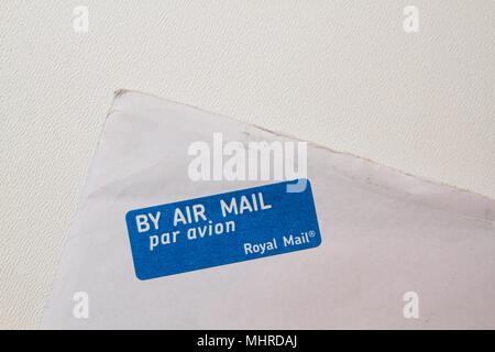 White envelope corner. By air mail par avion by Royal Mail. By plane blue with white stamp, on the corner of an envelope, isolated on white. Stock Photo