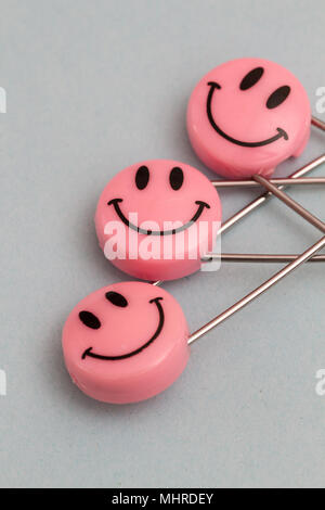 Plastic head metal safety pins pinned in paper. Pink smile