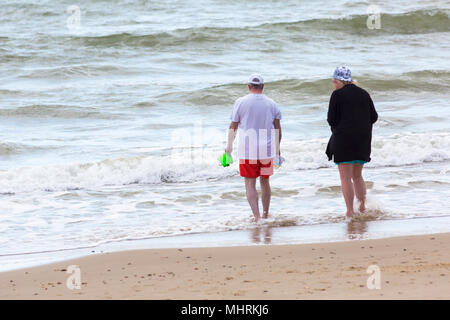 Bournemouth, Dorset, UK. 3rd May 2018. UK weather: cool sunny afternoon at Bournemouth beaches, as visitors enjoy the sunshine at the seaside.  Senior couple paddling in the sea with man carrying buckets. Credit: Carolyn Jenkins/Alamy Live News Stock Photo