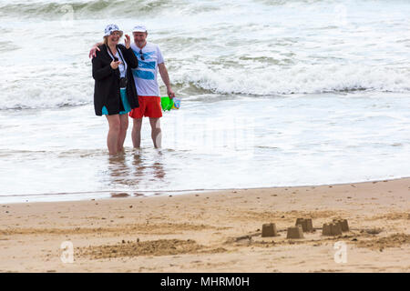 Bournemouth, Dorset, UK. 3rd May 2018. UK weather: cool sunny afternoon at Bournemouth beaches, as visitors enjoy the sunshine at the seaside. Senior couple having fun in the sea with man carrying buckets. Credit: Carolyn Jenkins/Alamy Live News Stock Photo