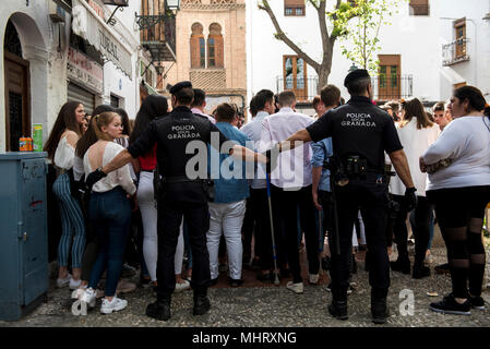 Policemen try to empty Plaza Larga Square of people during the Dia de las Cruces festival.'El día de la Cruz”or  “Día de las Cruces” is one of the most beautiful festivities in Granada. Each 3rd of May many streets, squares and terraces show altars with crosses decorated with flowers to commemorate the Holy Cross. Stock Photo