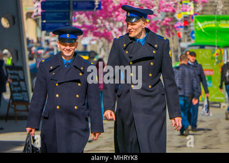 MOSCOW, RUSSIA- APRIL, 24, 2018: Outdoor view of two men wearing uniform and walking under a festive Christmas lights on Nikolskaya streets in a sunny day Stock Photo