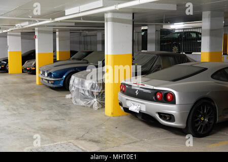 Expensive luxury cars in an underground car park in Montreal Quebec. They are covered in dust as they have not been used in years. Stock Photo