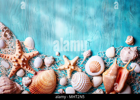 Summer time concept with seashells and starfish on blue wooden boards. Rest on the beach. Background with copy space Stock Photo