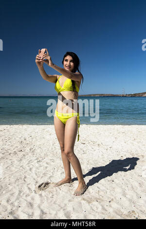 beautiful latina woman taking a selfie in studio with pink background