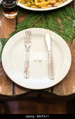 decor, party, medicine concept. there is a top view of the white plate with silverware and pills, it is placed on the wooden table that is decorated with spruce branch Stock Photo
