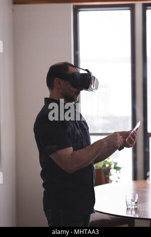 Male executive using virtual reality headset with glass digital tablet Stock Photo