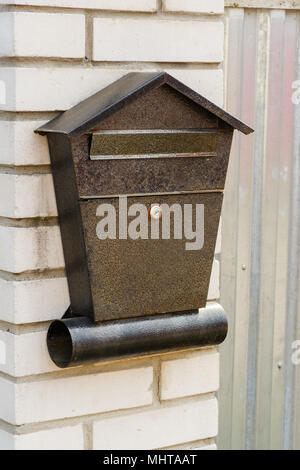 A metal mailbox on a brick wall hangs Stock Photo