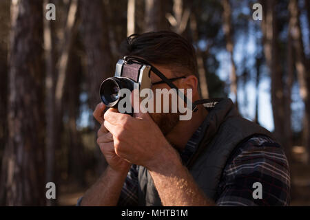 Man clicking photo with vintage camera in forest Stock Photo