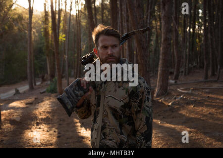 Hunter with bow and arrow standing in forest Stock Photo