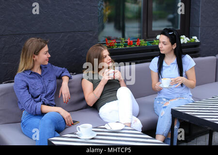 Female friends laughing and talking at cafe. Stock Photo