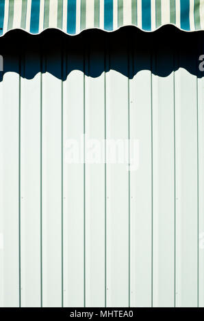 striped tent projecting a shadow on a white wall Stock Photo