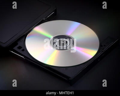 A silver, shiny CD is shown ejected in the tray of a portable multimedia disc player. Stock Photo