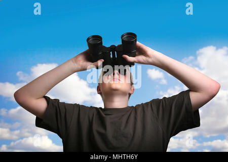 Boy looking through binoculars against sky Stock Photo