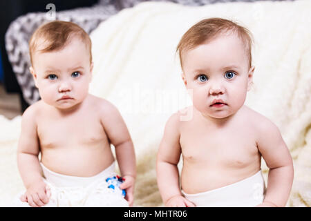 Two adorable baby twins sitting in the chair. Stock Photo