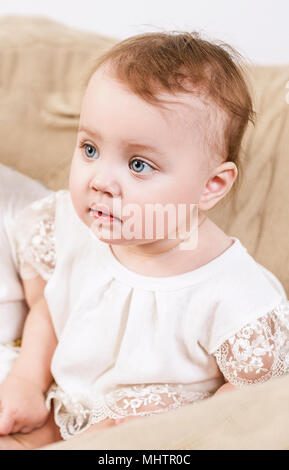 Little baby girl sitting in high chair at home and playing with toys ...