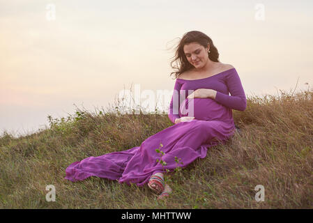 Young pregnant woman waiting for baby in natural background Stock Photo