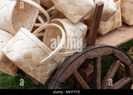 White wooden baskets made of bast in a pile on a vintage cart. Wooden wheel with a metal rim is partly visible Stock Photo