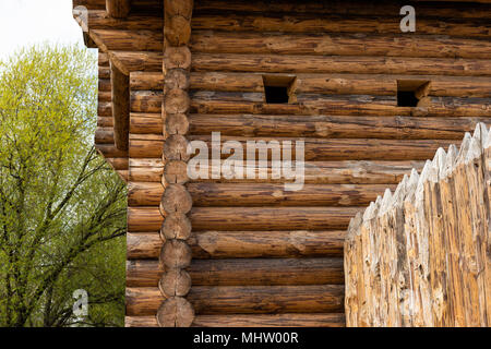 Detail of a watchtower made of wooden logs and a palisade or picket wooden fence. Two square arrow or gun holes are visible Stock Photo