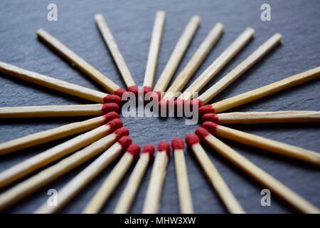 Collection of red head matches laid out in a heart forming shape on a black grey slate background. Stock Photo