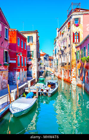 Narrow side canal with moored motorboats in Venice on sunny day, Italy Stock Photo