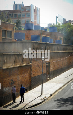 Two men stand and talk at a street  Central Business District of Johannesburg, South Africa. Stock Photo