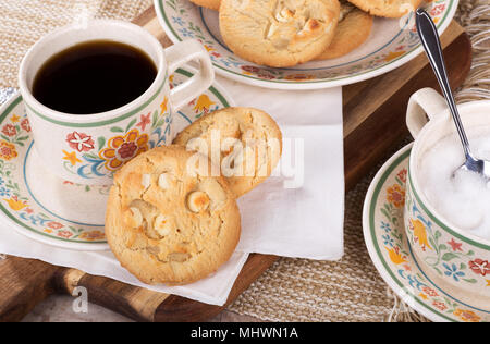 Macadamia nut cookies and cup of coffee on a plate with a plate of cookies and bowl of sugar Stock Photo