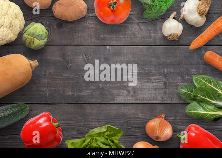 Composition of fresh vegetables spread on a wooden surface. Copy space in the middle. Stock Photo